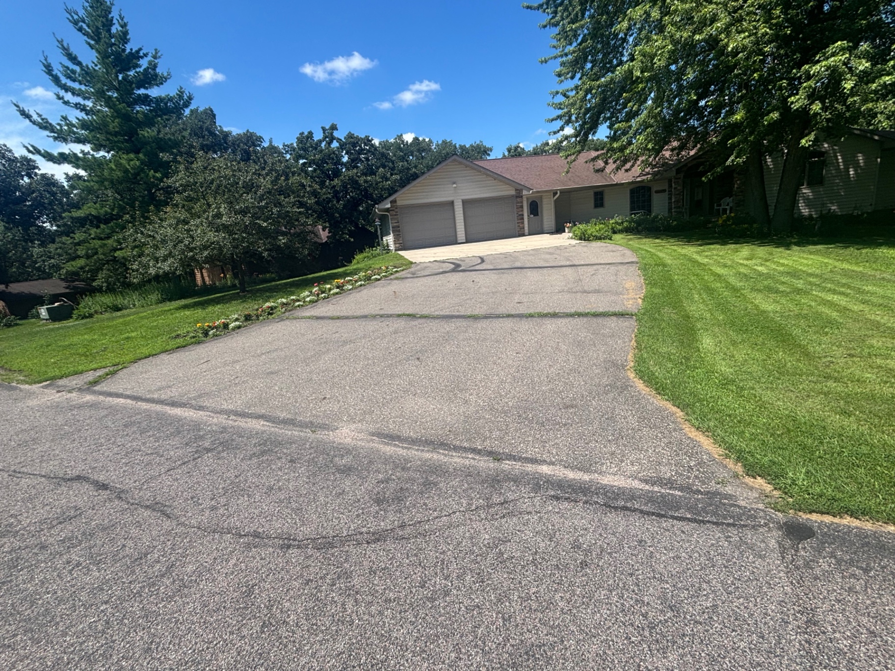 Cracked, faded gray asphalt driveway before seal coating