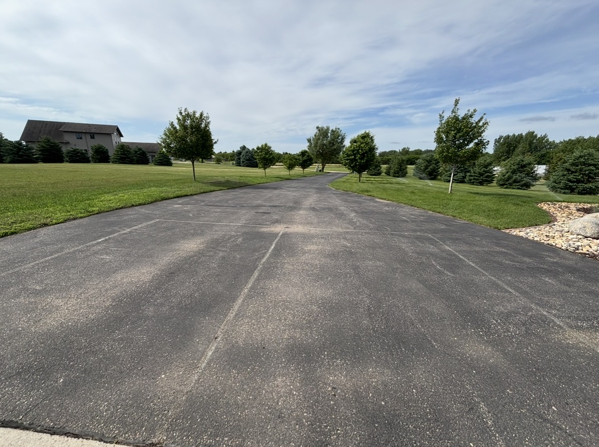 Weathered asphalt driveway with visible seams before sealing